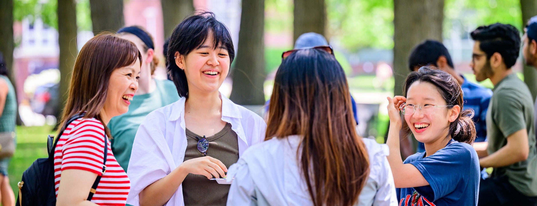 Students huddle up with their popsicle treats as students and staff play cornholde as they gather for “Summer Fun at Illini Grove!” for a summer afternoon of classic picnic snacks