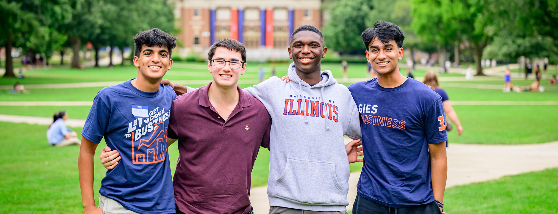 four students smiling and embracing on the main quad